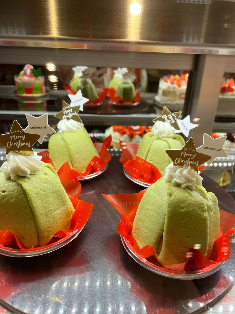 Festive green cakes with 'Merry Christmas' toppers displayed in a Châteraisé pastry case.