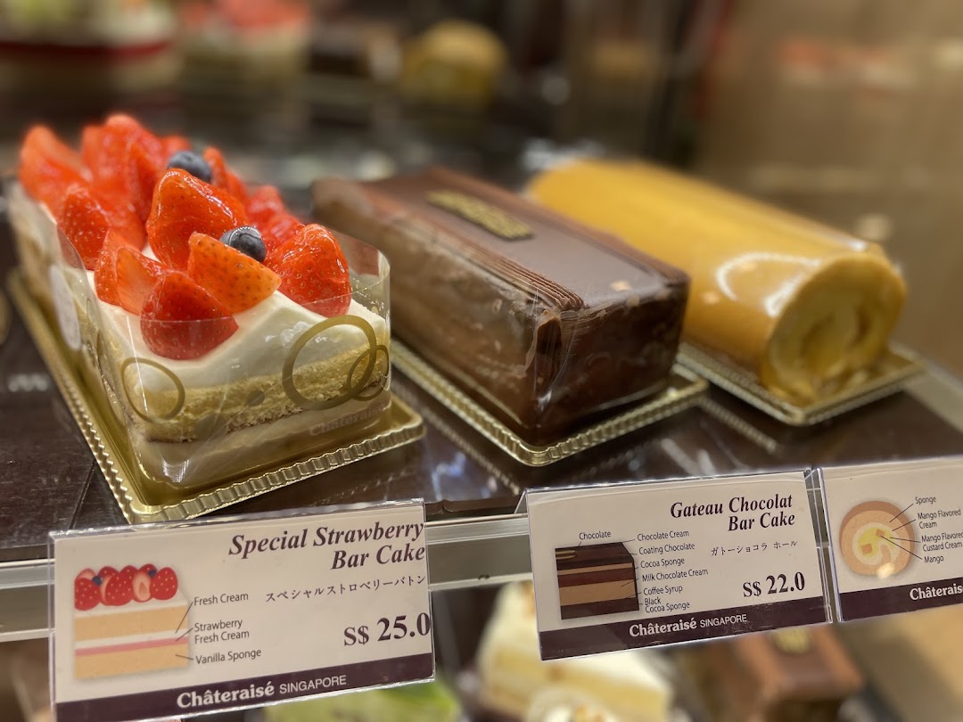 A display of delectable cakes, including strawberry and chocolate bar cakes, with price tags.