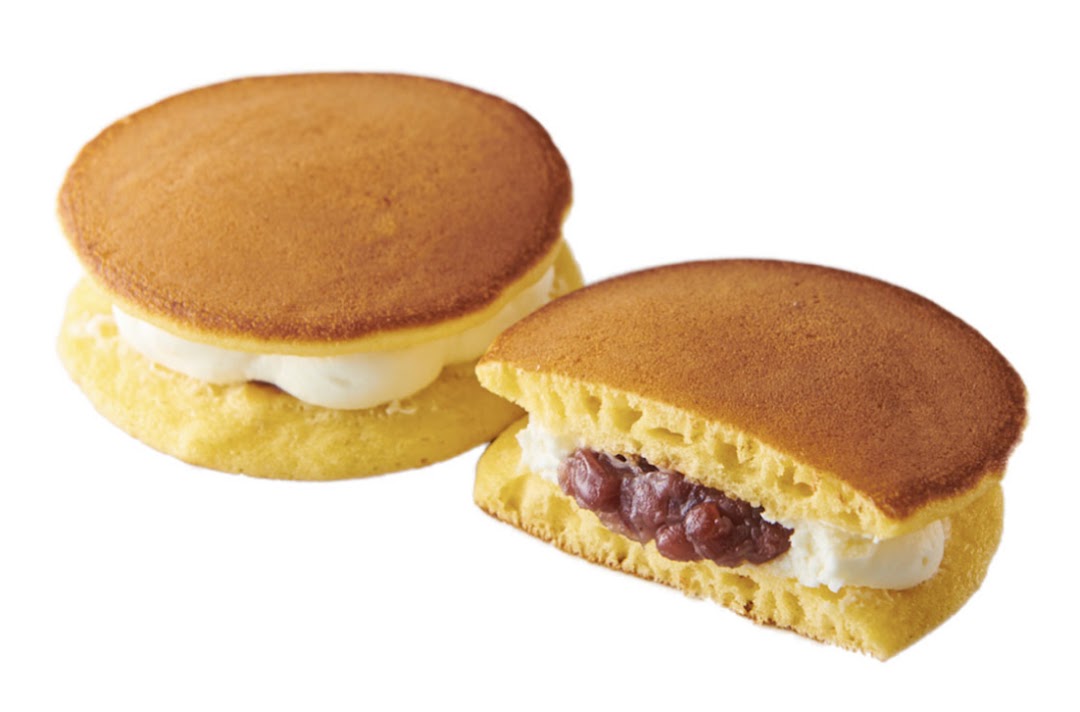 Two Japanese dorayaki pancakes, one whole with cream, one cut revealing red bean paste and cream.