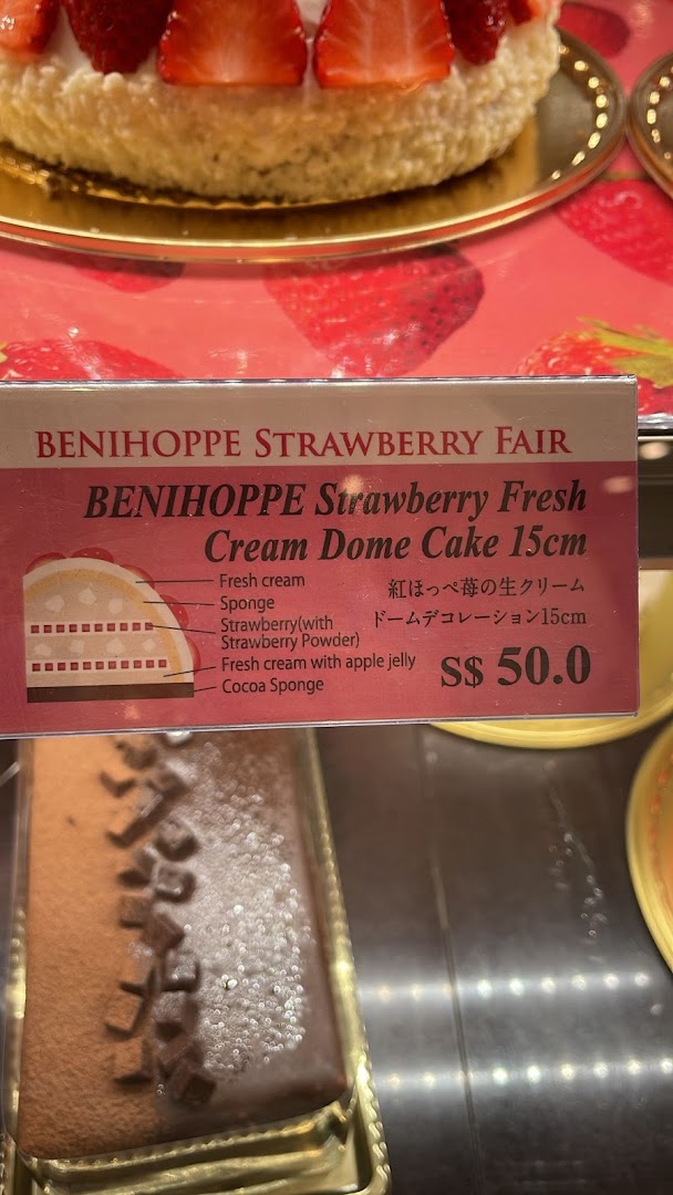 A display of a strawberry cream dome cake with a detailed product information sign.