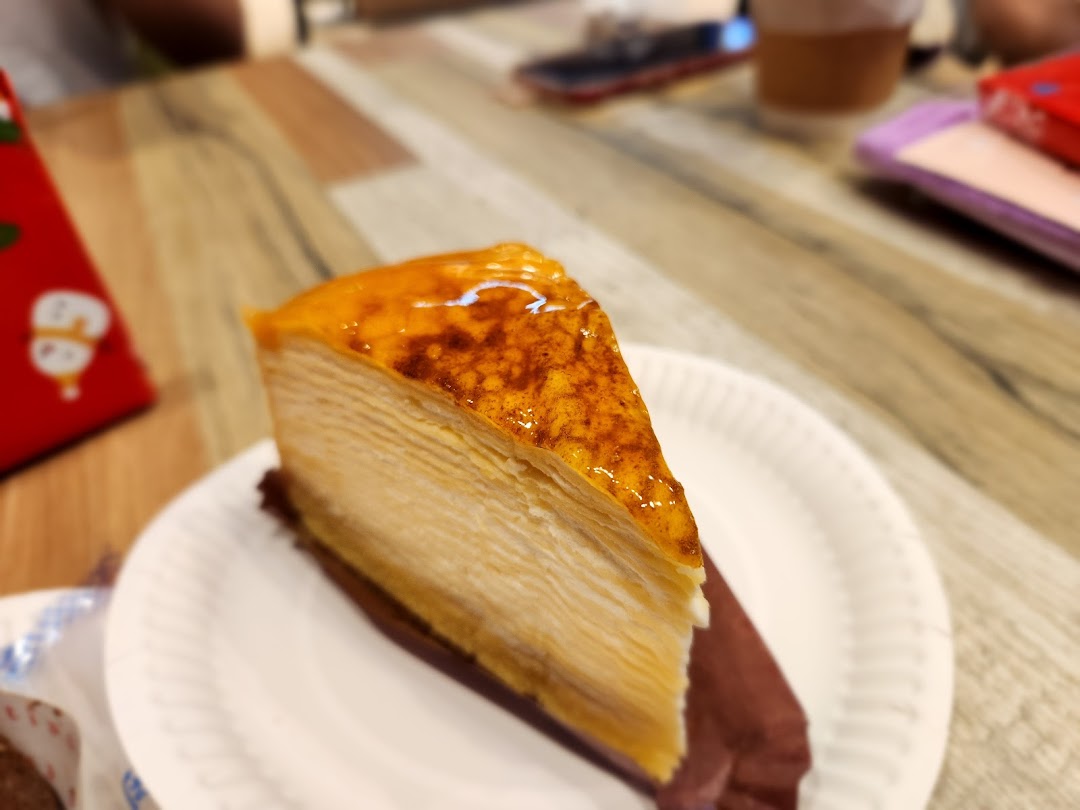 A delicious slice of golden-topped mille crepe cake on a white plate.
