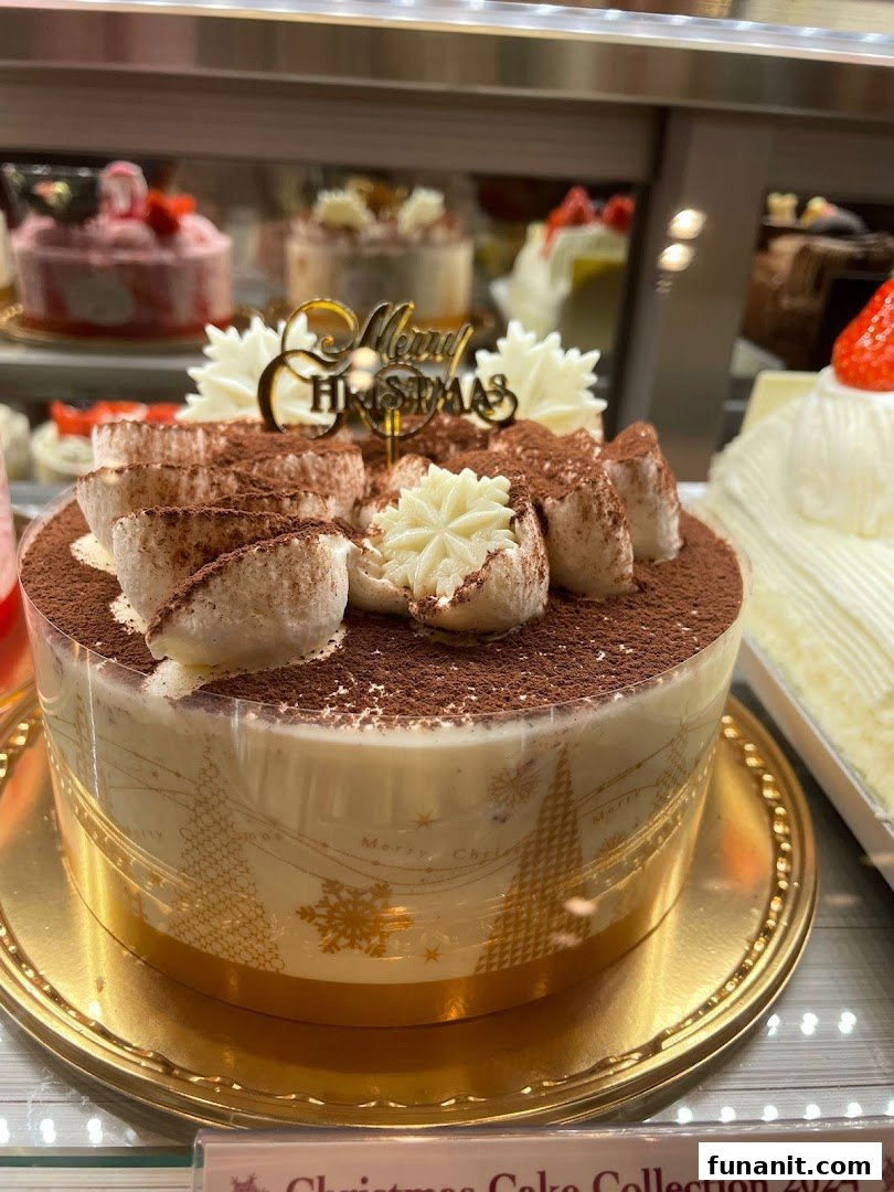 A beautifully decorated Christmas cake with a 'Merry Christmas' topper in a display case.