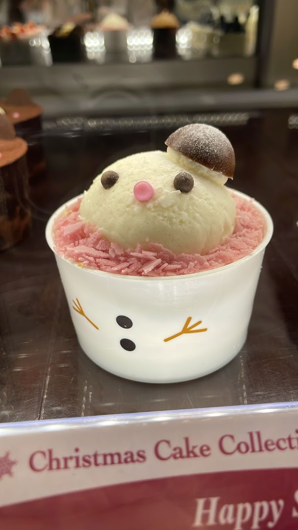 A charming snowman-themed dessert with white cream and pink sprinkles in a cup.