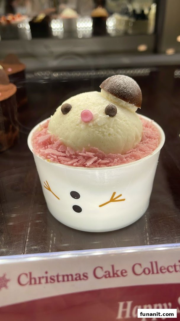 A charming snowman-themed dessert with white cream and pink sprinkles in a cup.
