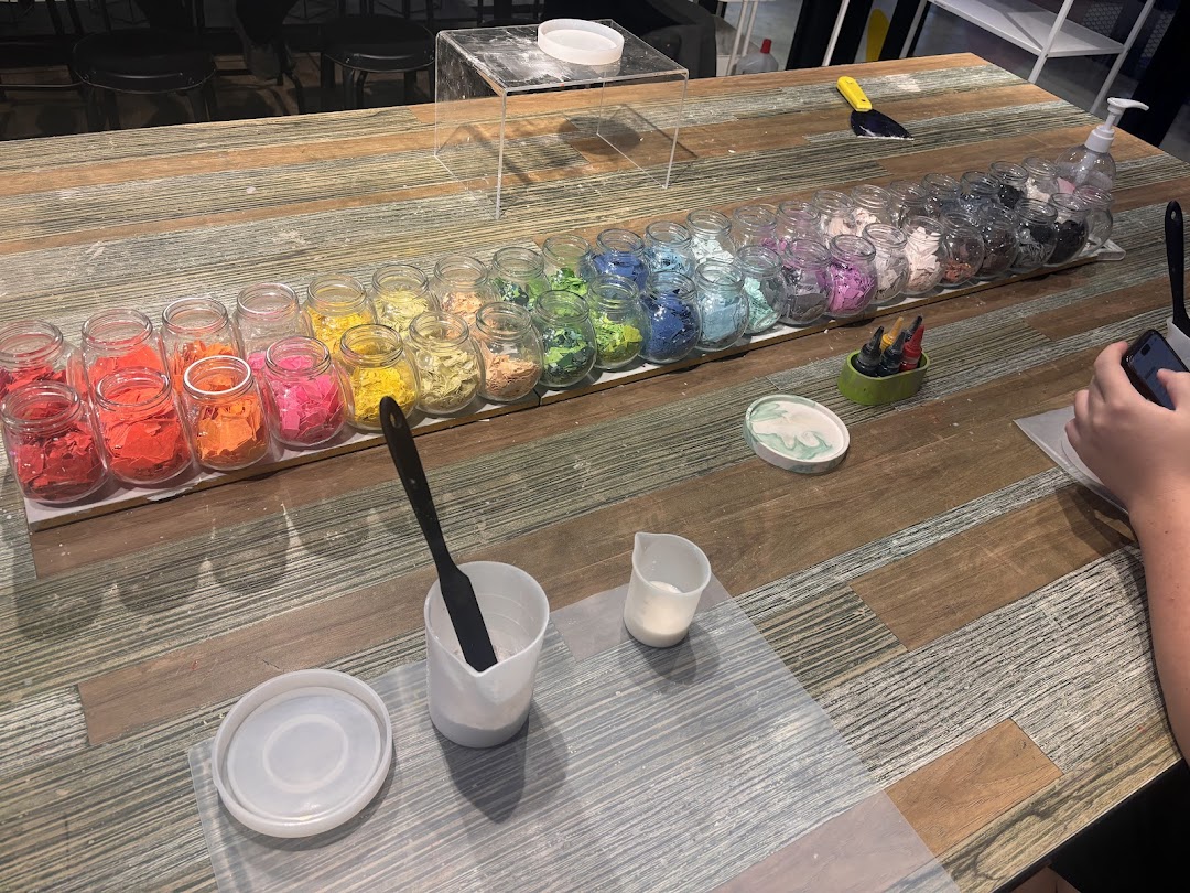 A crafting station with colorful flakes in jars, mixing tools, and molds for creative workshops.