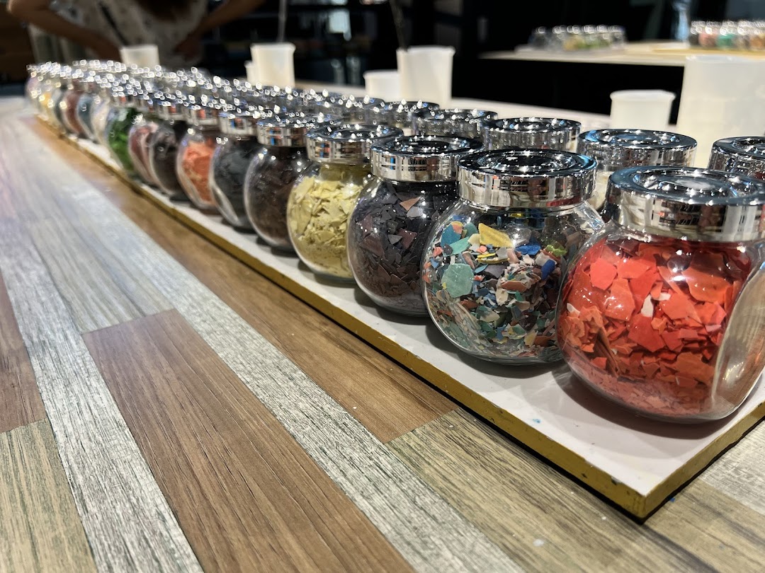 Rows of glass jars filled with colorful, textured materials for creative projects.