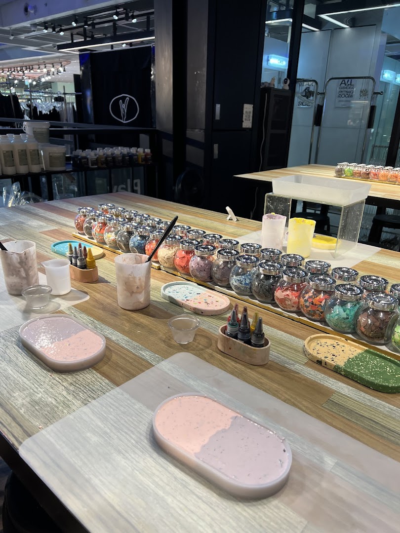 A crafting workshop table with colorful materials, liquid dyes, and partially finished resin art pieces.
