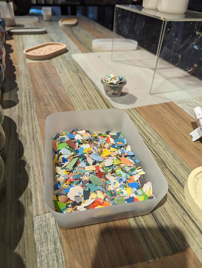 A close-up of colorful recycled material chips in a container on a wooden table, ready for crafting.