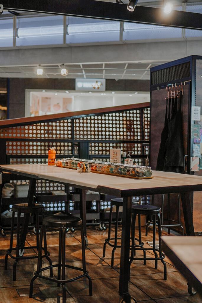 Interior view of Chokmah, featuring a long communal table with stools and colorful product displays.