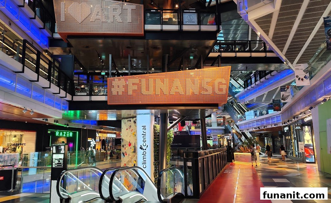 Interior view of Funan mall, showcasing escalators, various shops, and a glimpse of Climb Central's climbing wall.