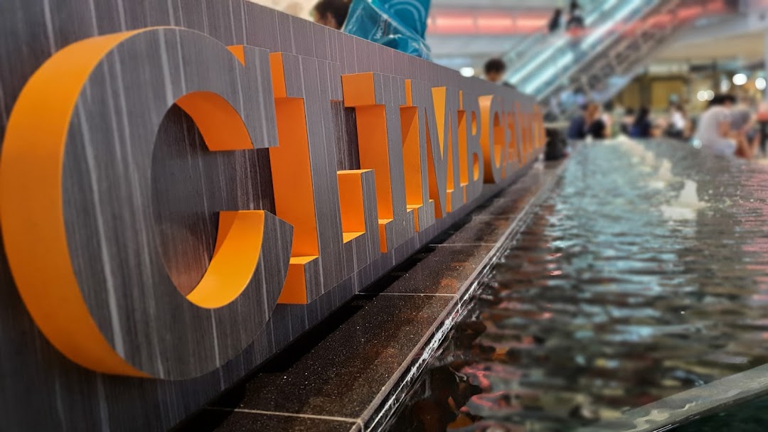 Close-up of the 'Climb Central' sign, partially submerged in a water feature within a bustling mall.
