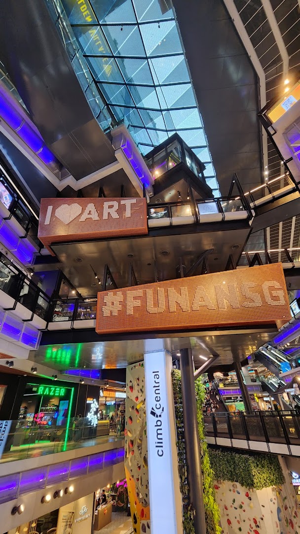 A multi-level mall interior featuring a prominent indoor climbing wall and the Climb Central sign.