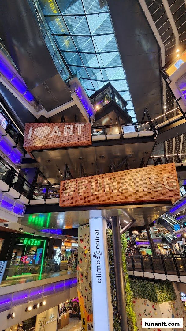 A multi-level mall interior featuring a prominent indoor climbing wall and the Climb Central sign.