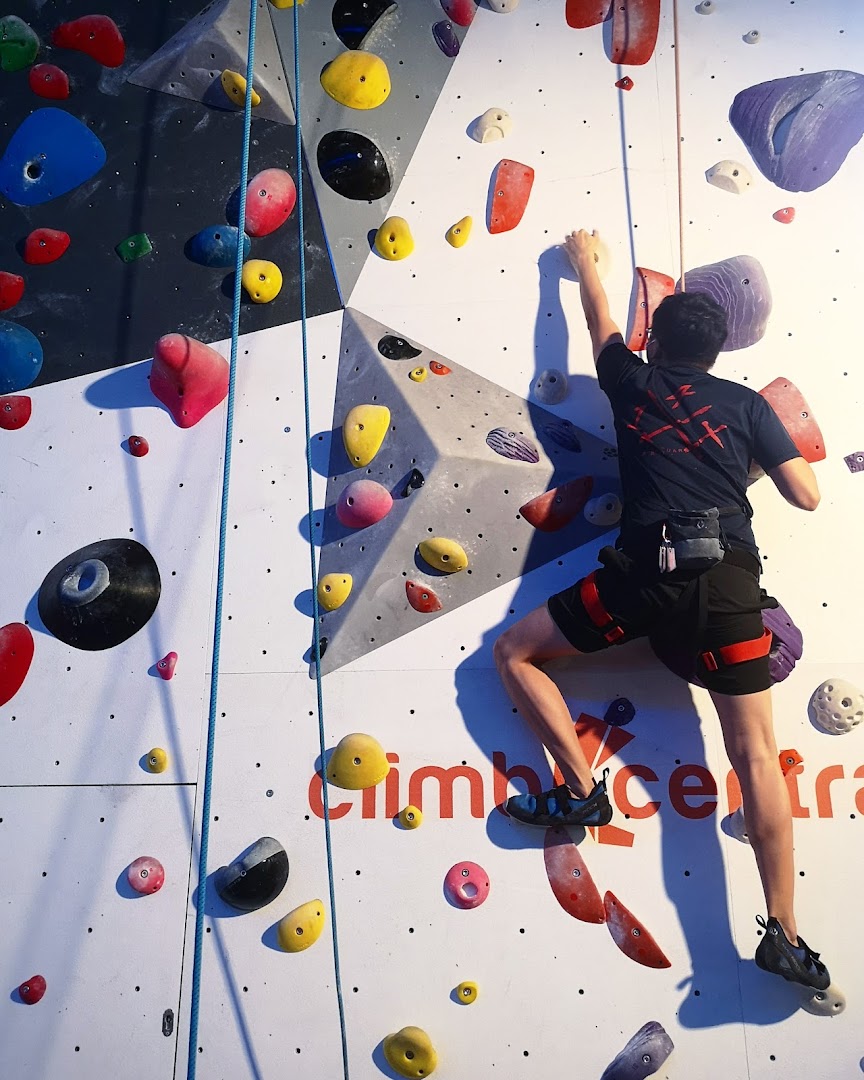 A climber ascends a vibrant indoor rock wall at Climb Central Funan.
