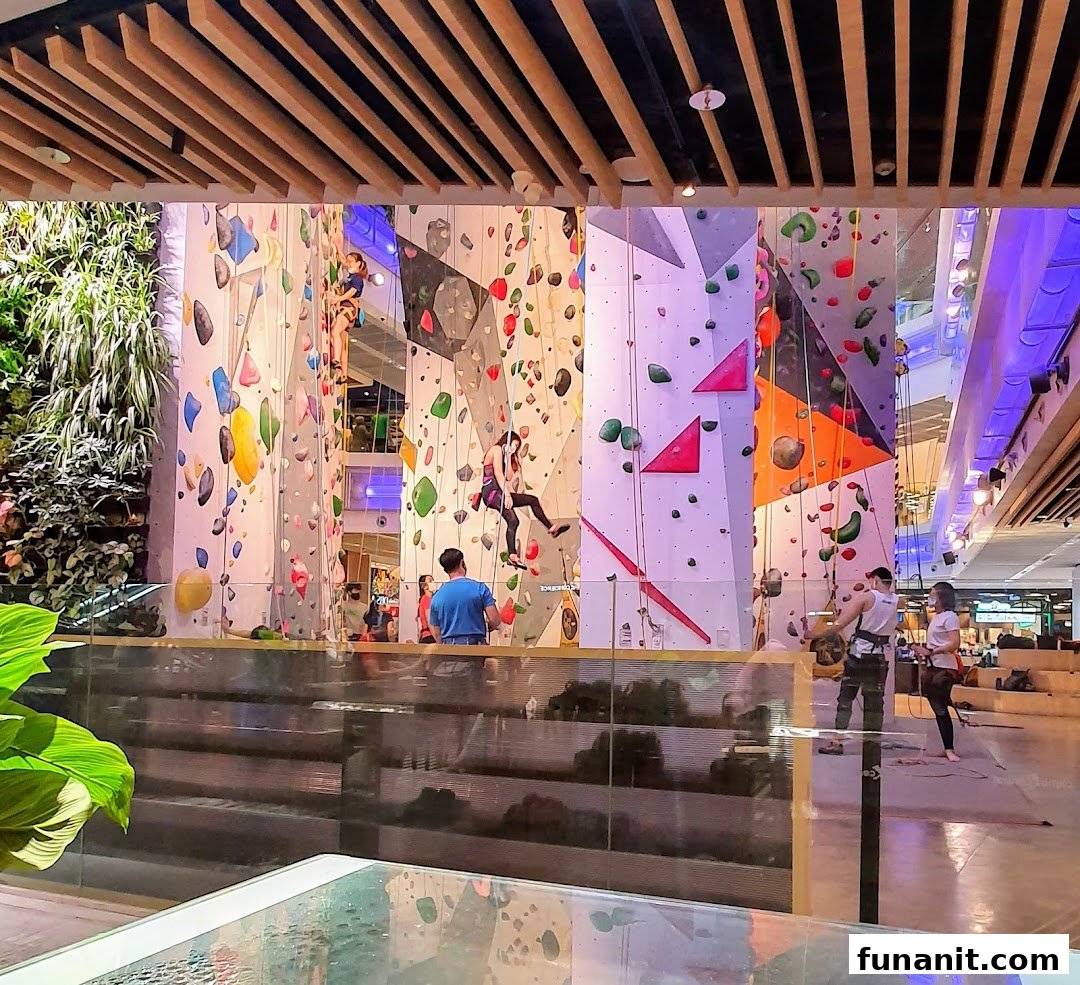 People are actively climbing on a vibrant indoor rock climbing wall at Climb Central Funan.