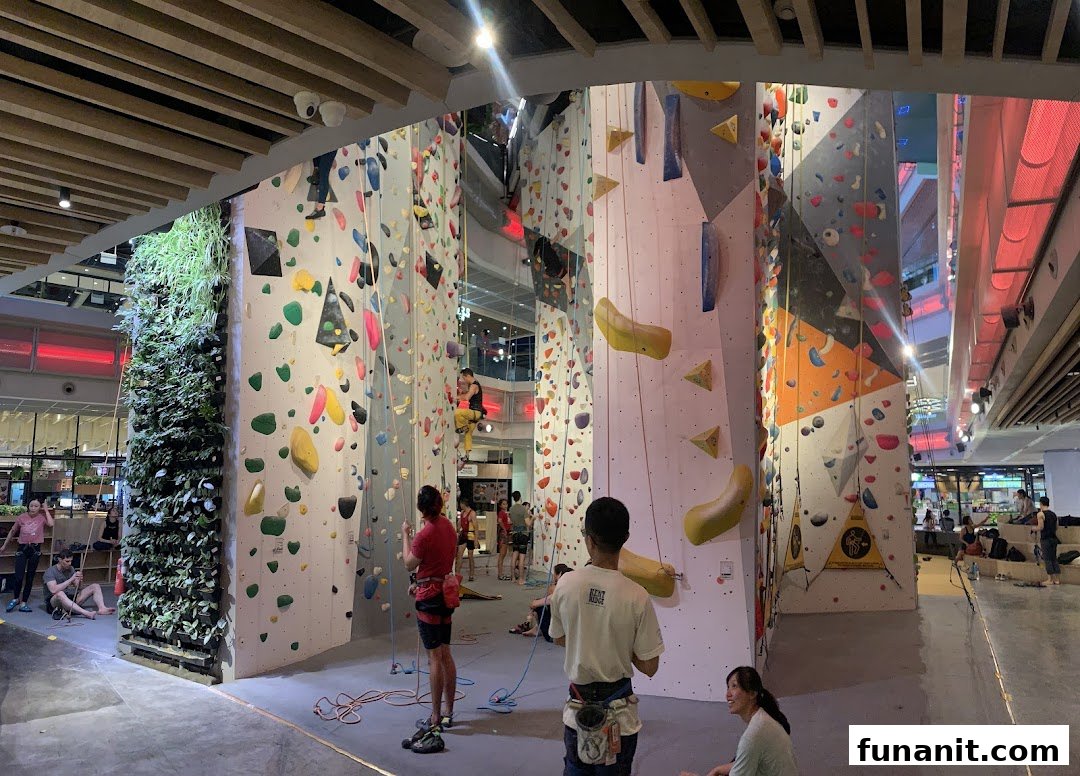 People engaged in indoor rock climbing on various colorful walls at Climb Central Funan.
