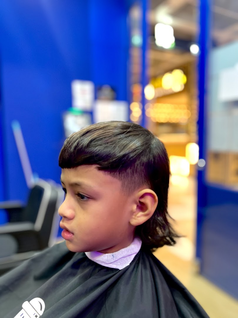 A young boy receiving a stylish haircut at Clippers Barber Funan, showcasing the shop's services.