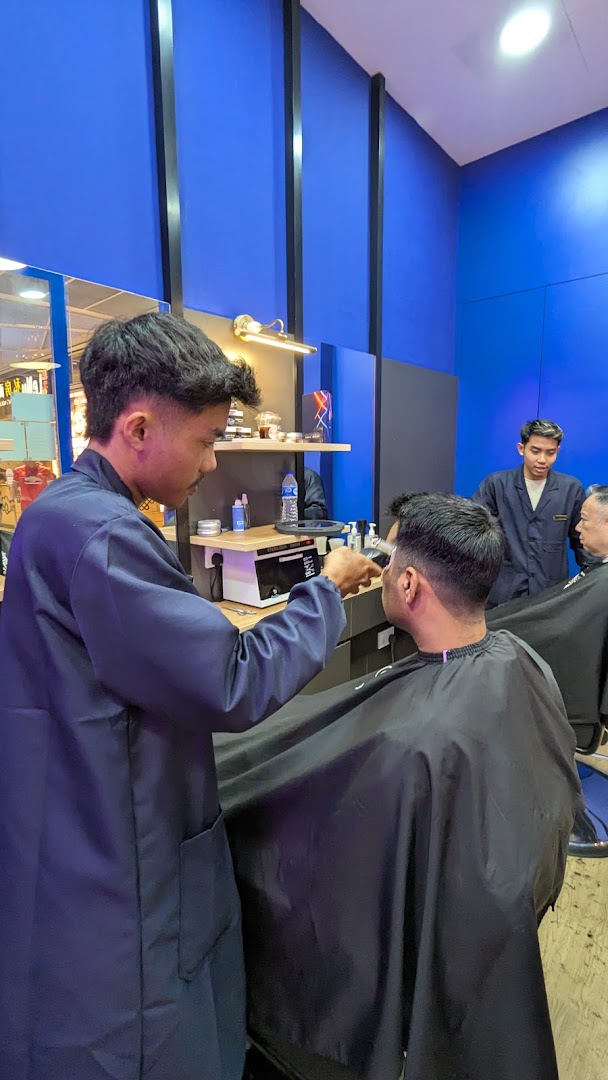 Barbers at Clippers Barber Funan providing haircuts to customers in a blue-themed interior.