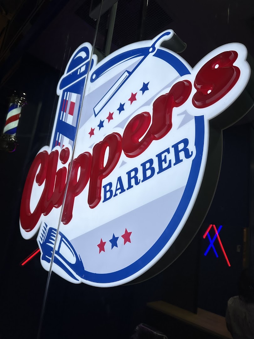 Close-up of the illuminated Clippers Barber shop sign with a traditional barber pole.