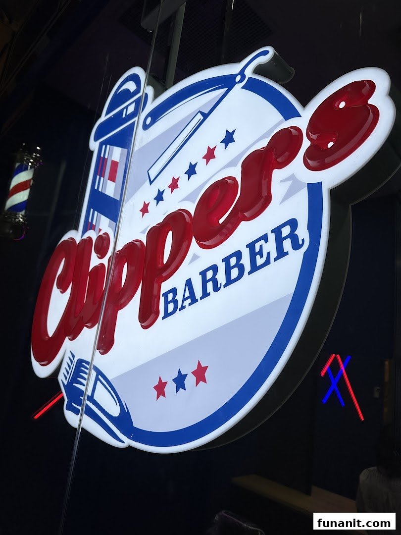 Close-up of the illuminated Clippers Barber shop sign with a traditional barber pole.