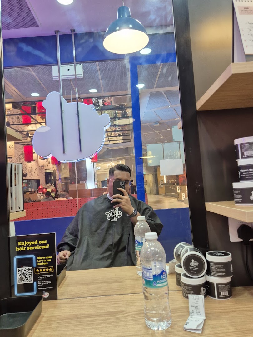 A customer in a barber's cape takes a selfie inside Clippers Barber Funan, showcasing the shop's interior.