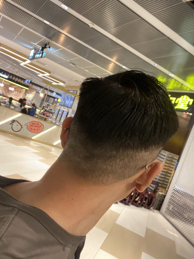 A person's head with a fresh haircut, viewed from behind, looking into a mall interior.