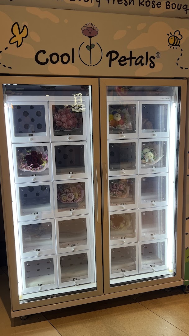 A 'Cool Petals' flower vending machine displaying various fresh rose bouquets and plush toys.