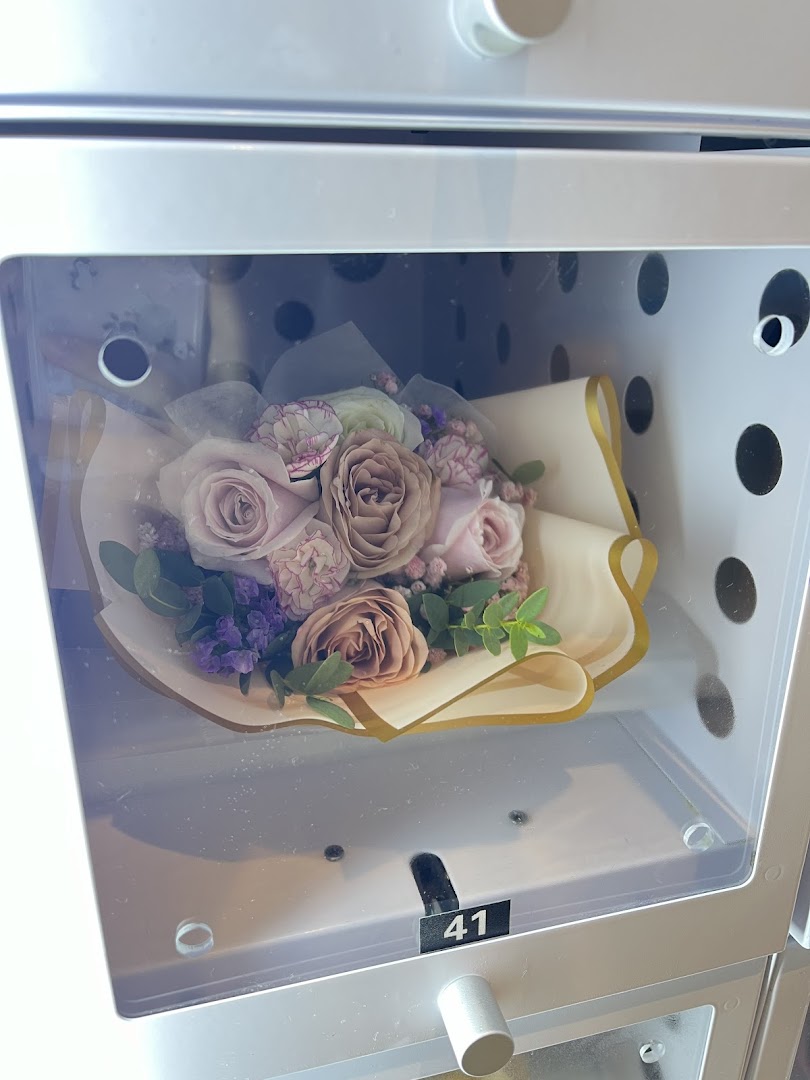 A beautiful bouquet of purple and pink flowers displayed inside a clear locker or vending machine.