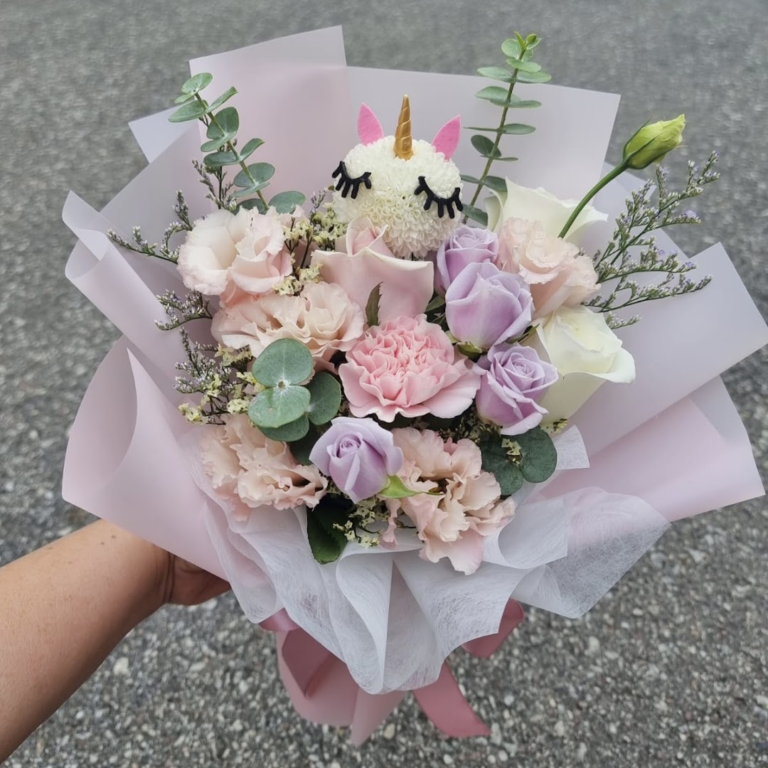 A charming pastel flower bouquet featuring a cute unicorn head, wrapped in pink and white paper.