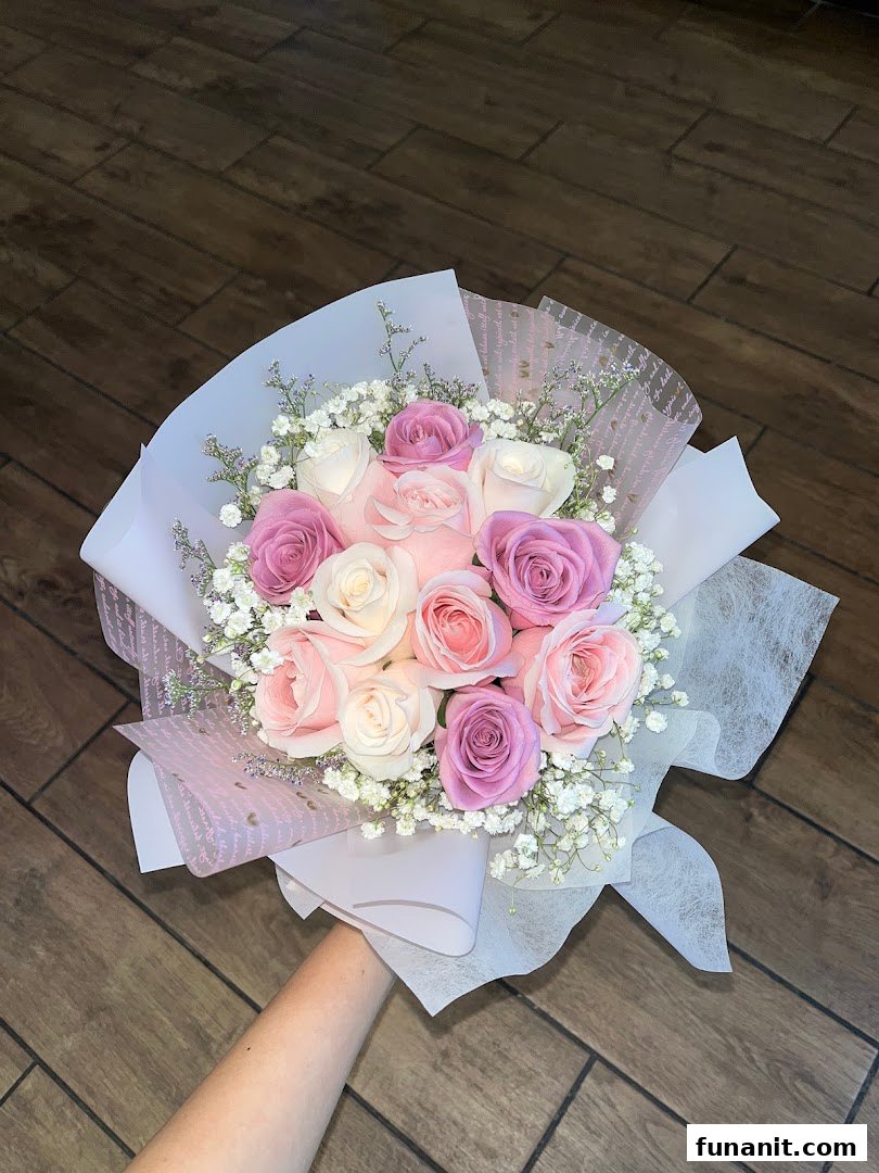 A beautiful bouquet of pink, purple, and white roses with baby's breath, elegantly wrapped.