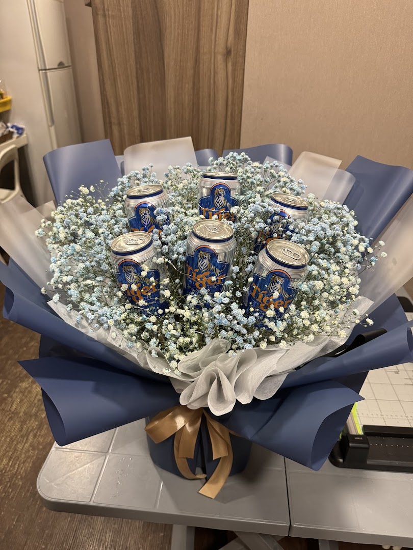 A unique bouquet featuring Tiger Beer cans nestled among blue and white baby's breath flowers.