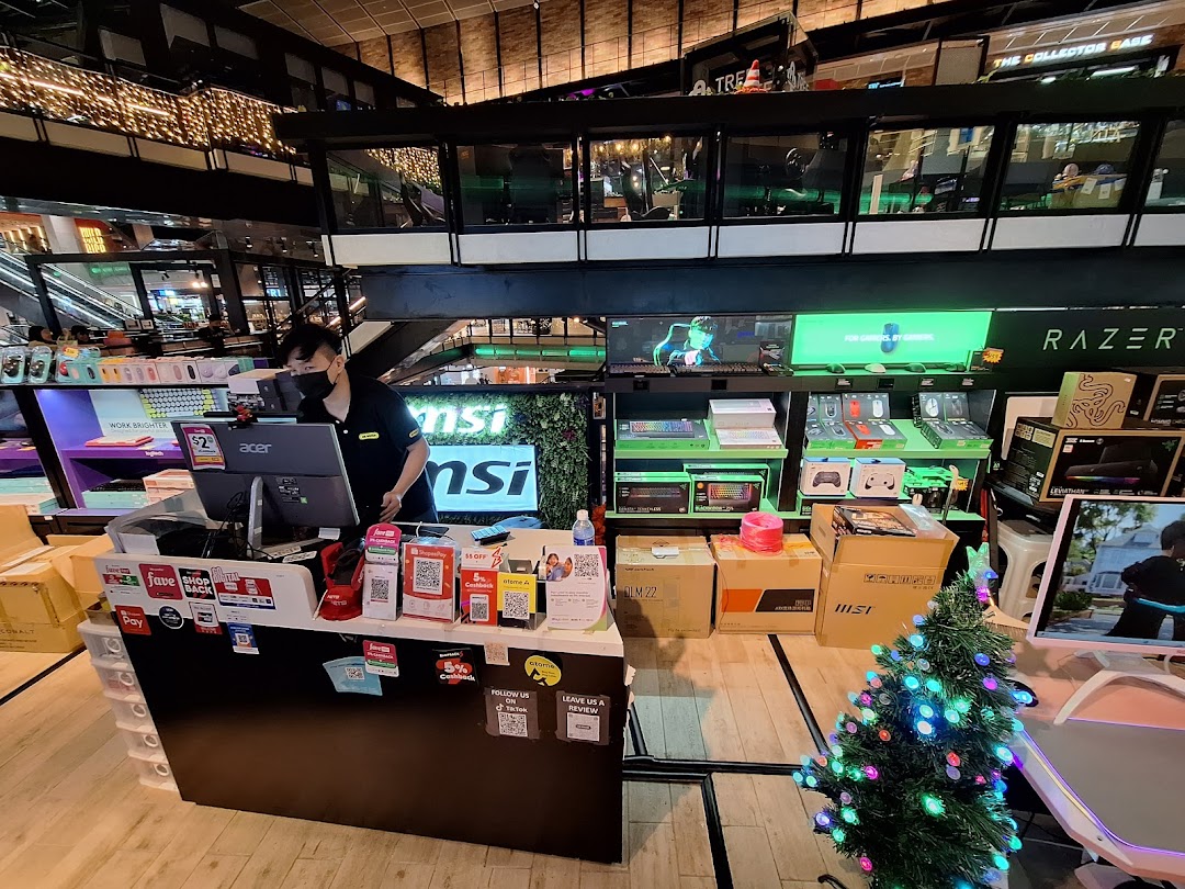 Interior view of CR GROUP, a tech and gaming store, with a staff member at the counter and various products.
