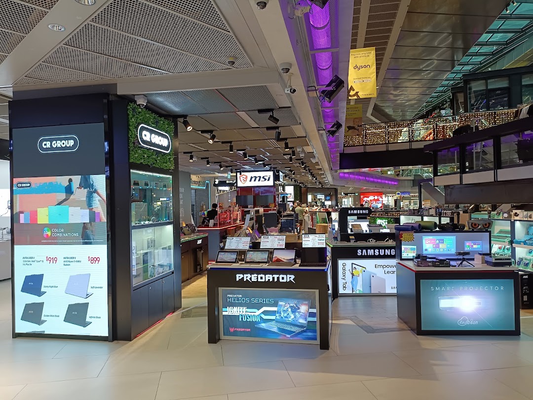 An interior view of CR GROUP, an electronics store showcasing laptops, smart projectors, and other tech products.