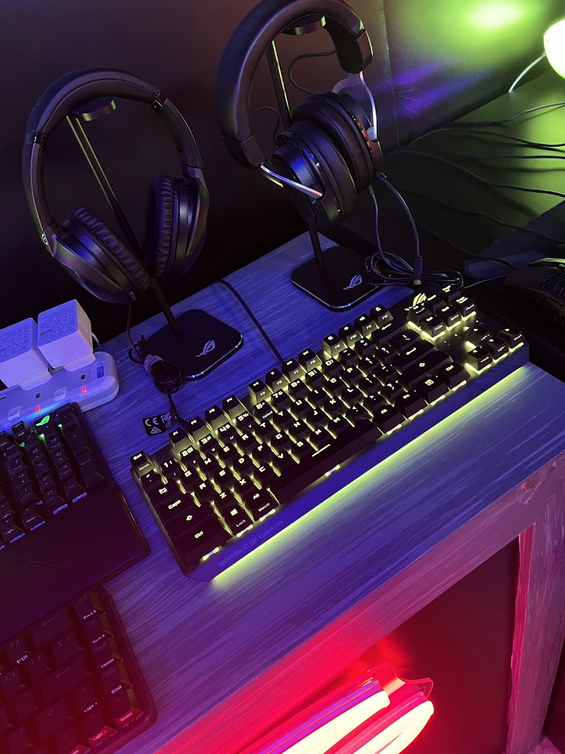 A vibrant display of gaming headsets and illuminated keyboards on a desk, showcasing modern tech.