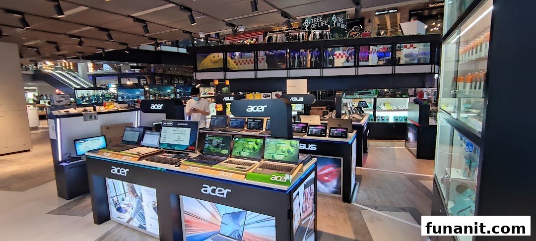 An electronics store interior showcasing a wide range of Acer and ASUS laptops and tech products.