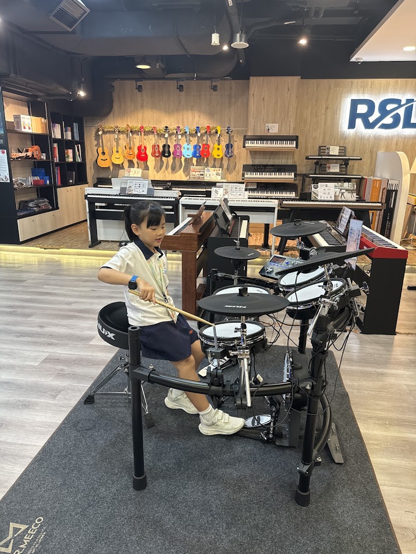 A child plays an electronic drum set inside Cristofori Music, surrounded by various musical instruments.