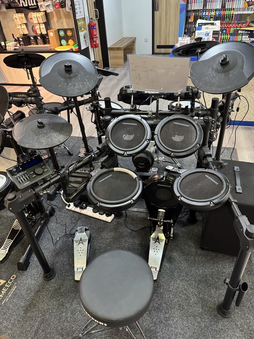 An electronic drum set with cymbals and pedals displayed on a grey mat in a music store.