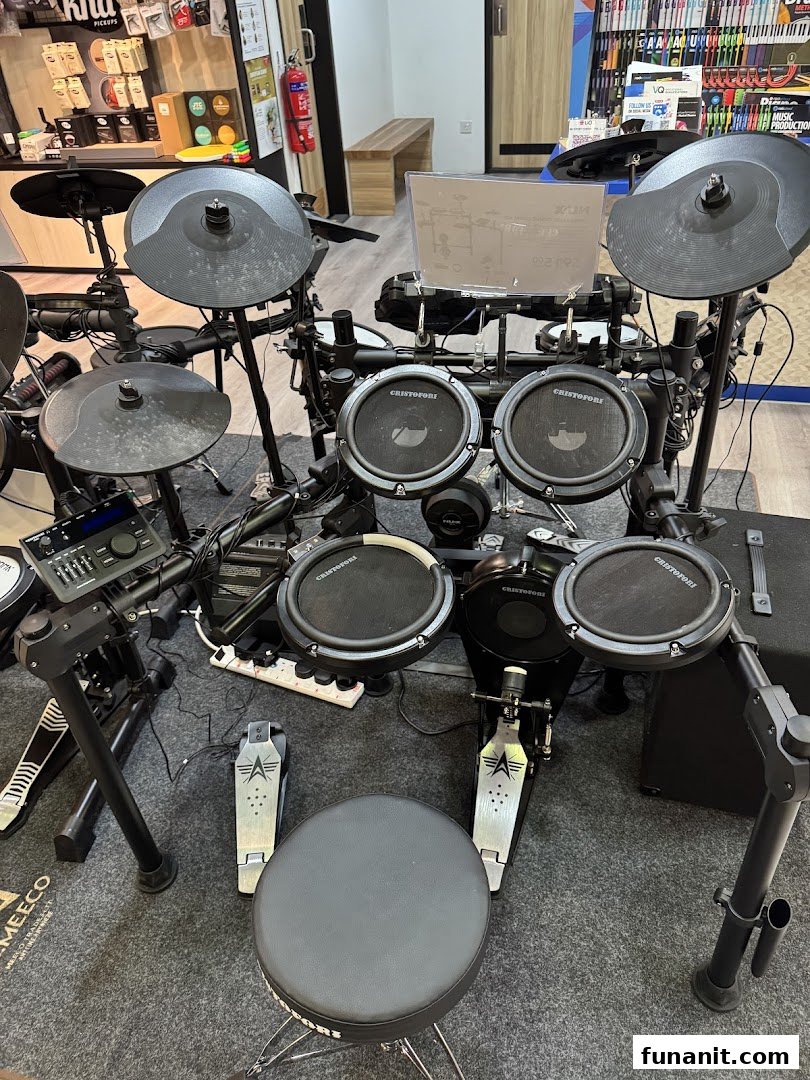 An electronic drum set with cymbals and pedals displayed on a grey mat in a music store.