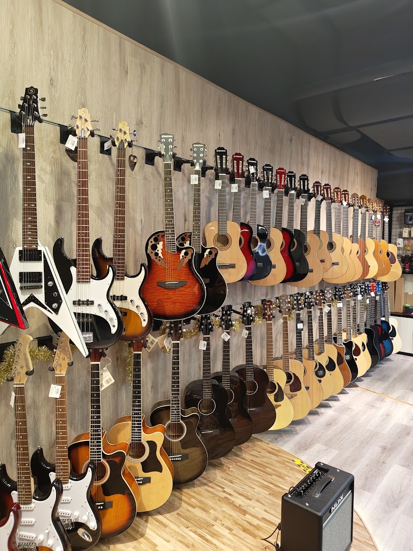 A wide array of acoustic and electric guitars displayed on a wall in a music store.