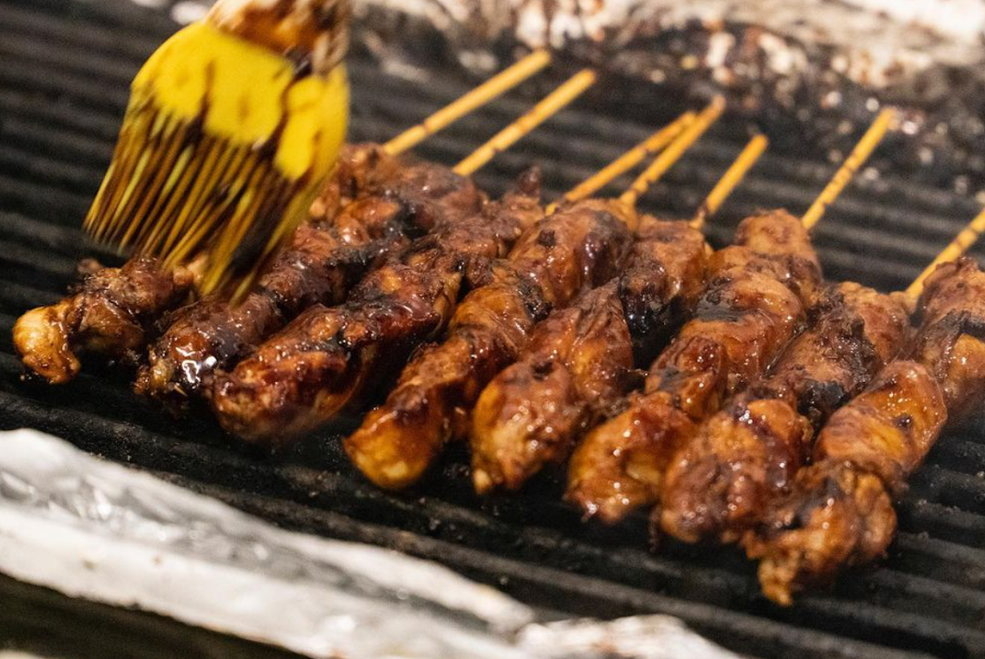 Delicious skewers of meat grilling on a barbecue, being brushed with savory sauce.