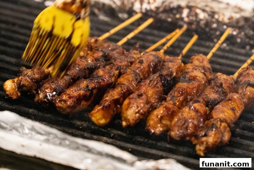 Delicious skewers of meat grilling on a barbecue, being brushed with savory sauce.
