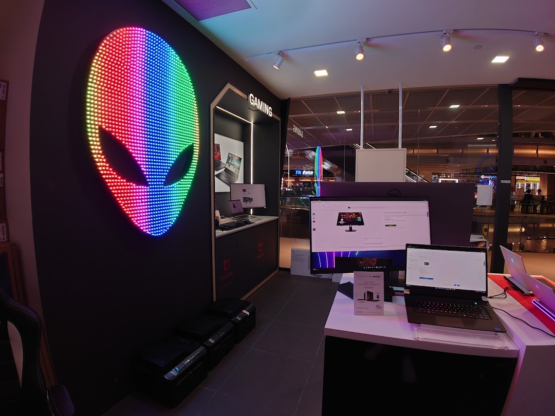 An Alienware gaming display inside a Dell Exclusive Store, featuring a vibrant LED alien head logo and gaming setups.