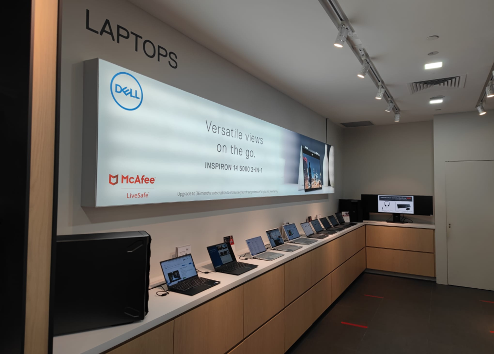 Interior view of a Dell Exclusive Store showcasing various laptops and a large promotional display.