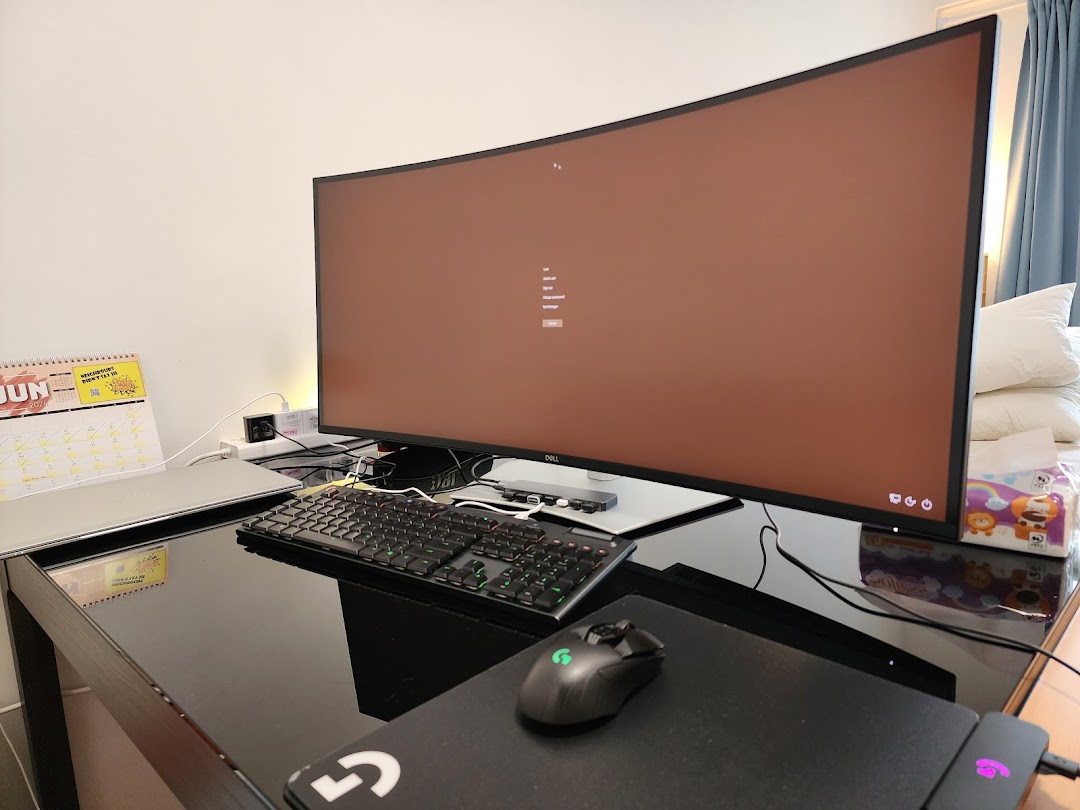 A large curved Dell monitor, keyboard, and mouse on a desk, showcasing a modern computing setup.