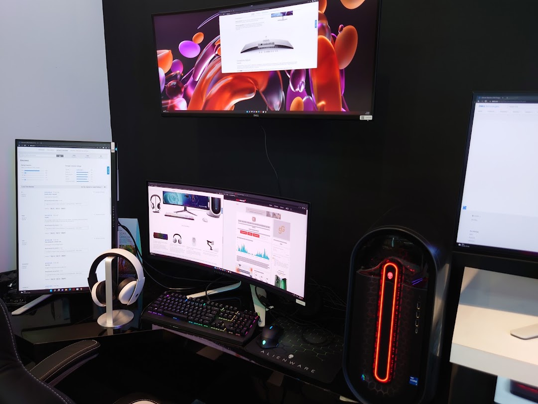 A high-performance Dell and Alienware gaming setup featuring multiple monitors, a PC, and headphones.