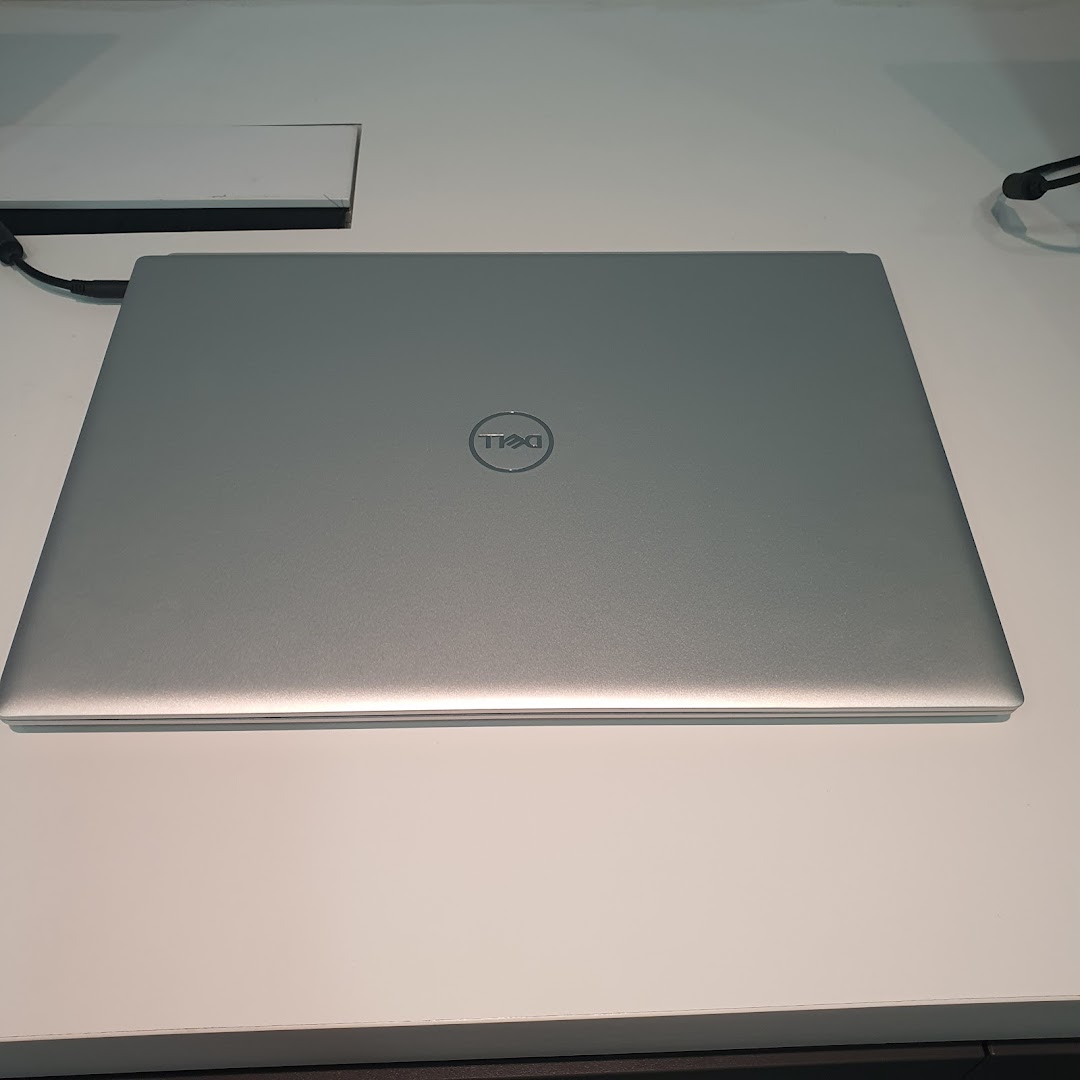 A silver Dell laptop with its lid closed, displaying the Dell logo on a white surface.