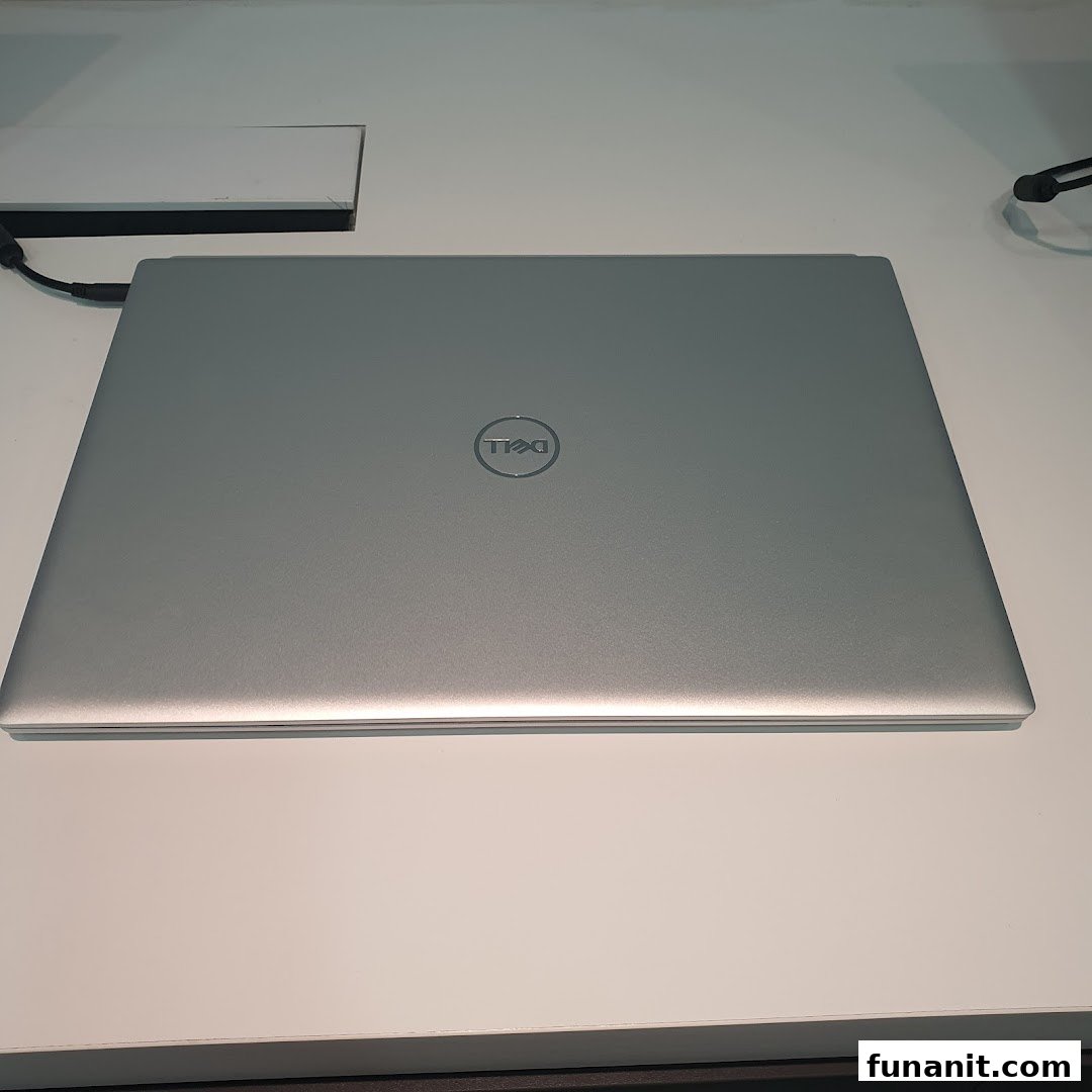 A silver Dell laptop with its lid closed, displaying the Dell logo on a white surface.