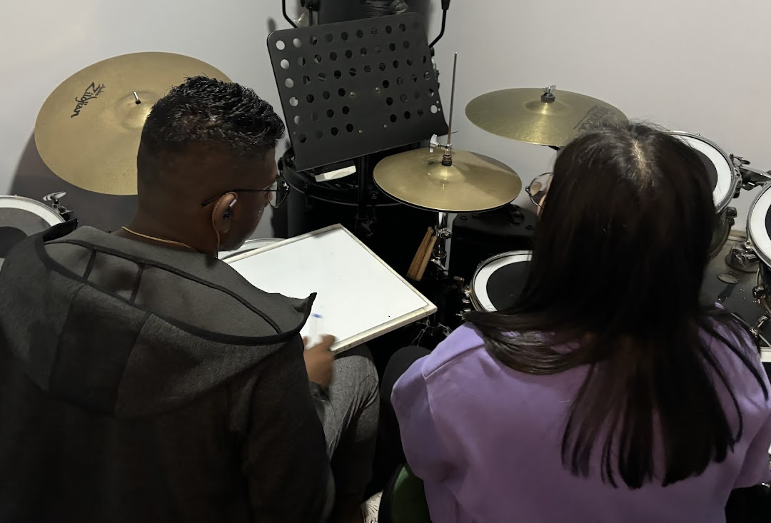 Two individuals engaged in a drum lesson or practice session at Drumstruck Studios.