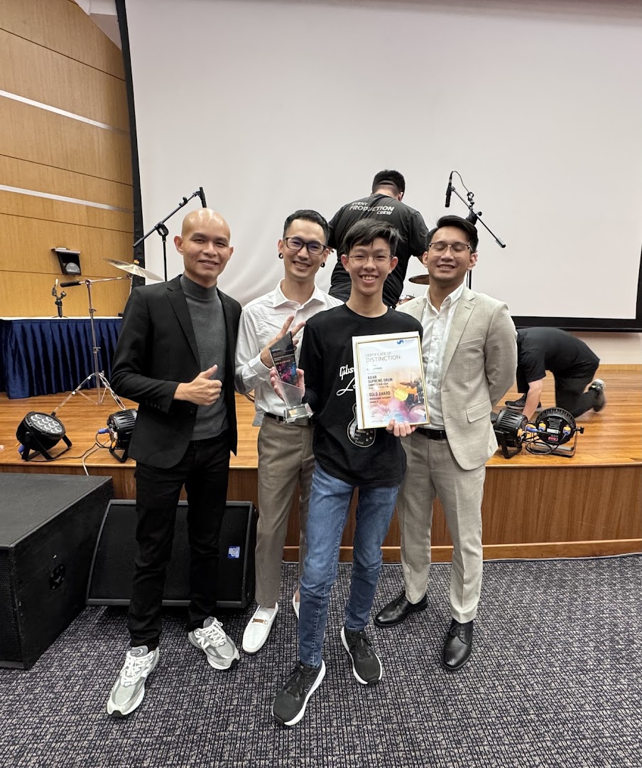 A group from Drumstruck Studios celebrates an award on stage, showcasing their musical excellence.