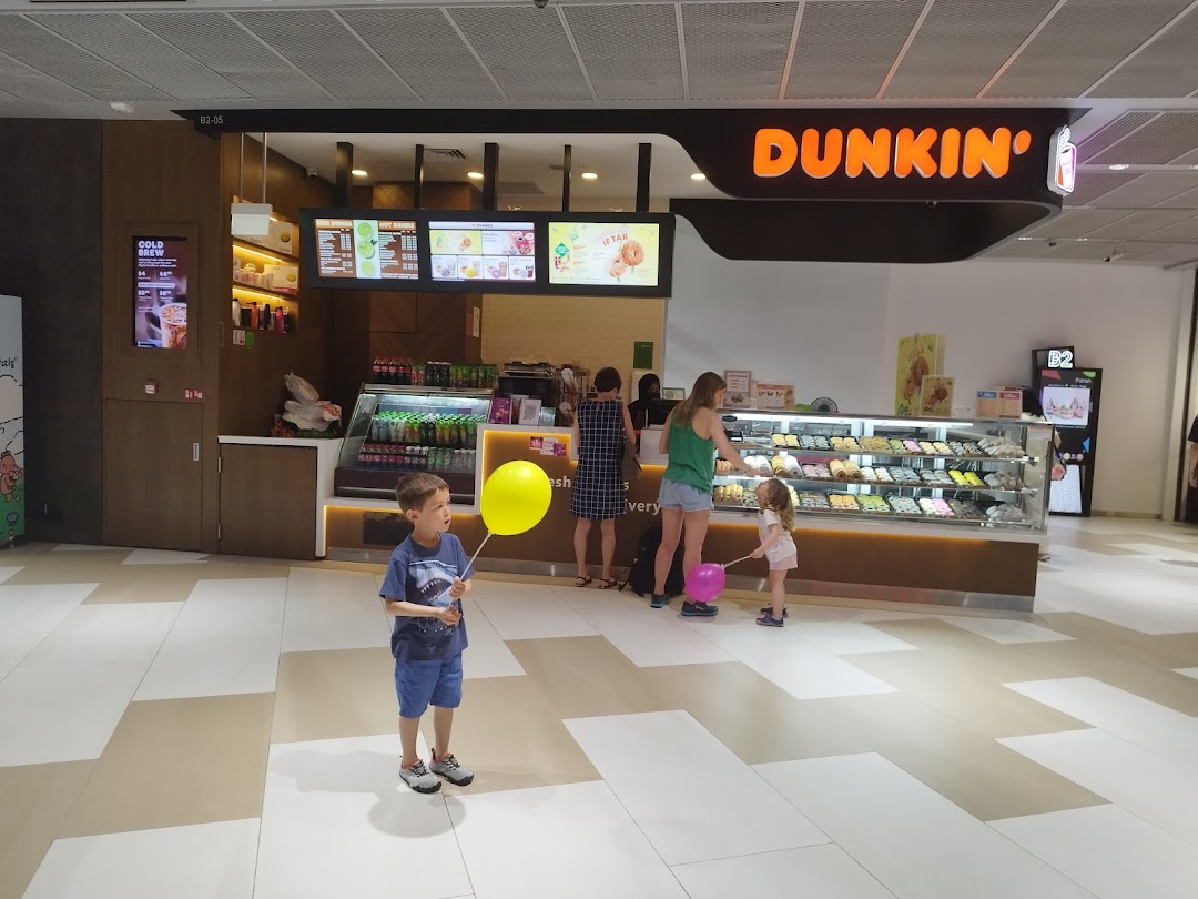 Customers browse delicious donuts and beverages at the vibrant Dunkin' Donuts counter.